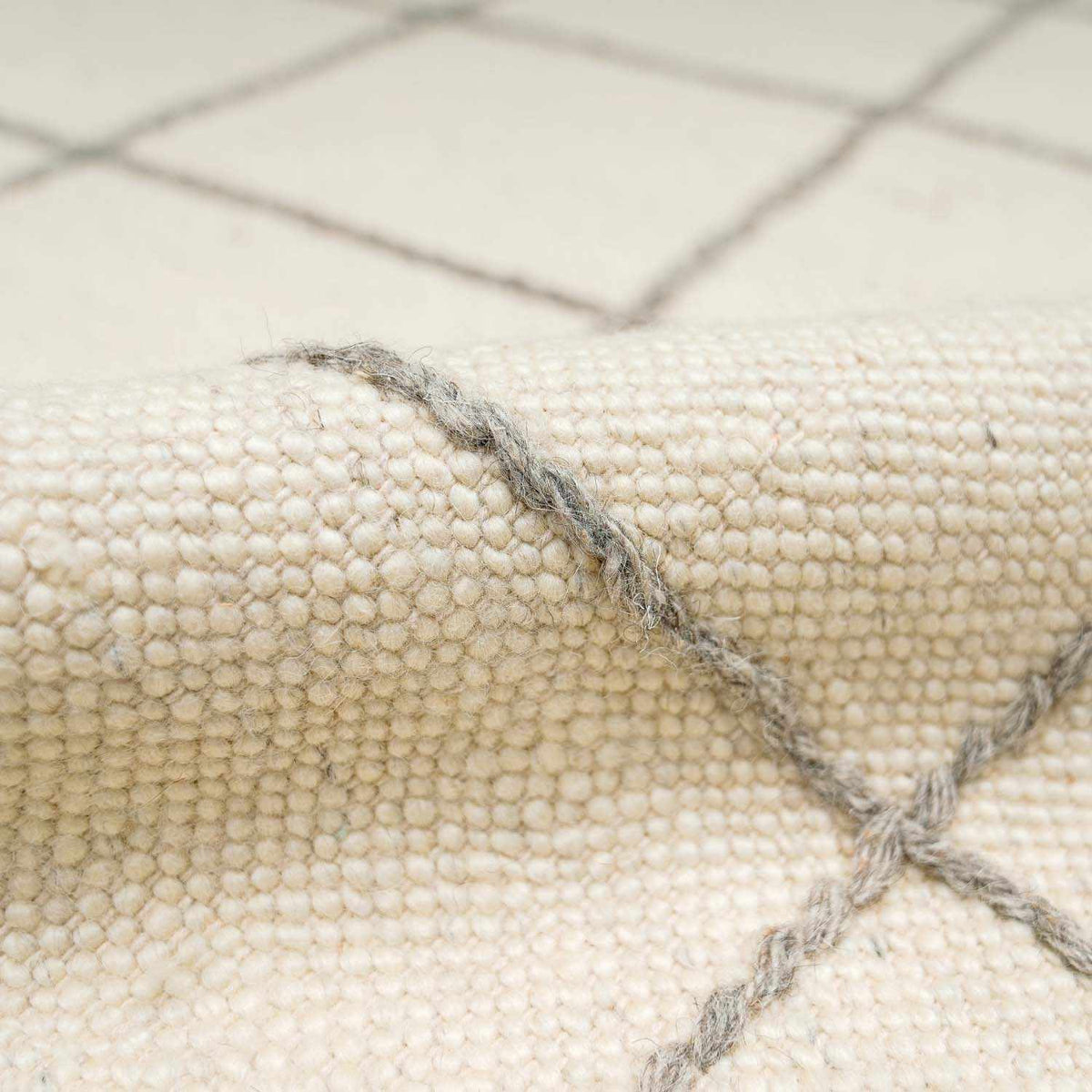 Cream wool rug with a hand-drawn gray grid pattern